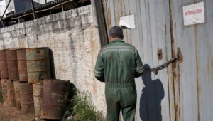 Portão de galpão industrial fechado com corrente e cadeado após interdição de atividade que funcionava sem licença ambiental